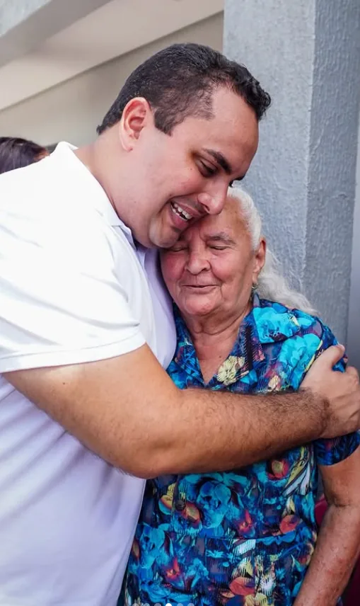 Georgiano Neto abraçando uma senhora durante visita à comunidade